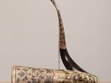 an old horn with a chain attached to it sitting on a table