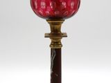 une lampe en verre rouge posée sur un pied doré