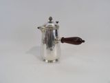 an antique silver coffee pot with a wooden handle on a white surface