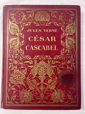 an old red book with gold writing on it sitting on a white surface
