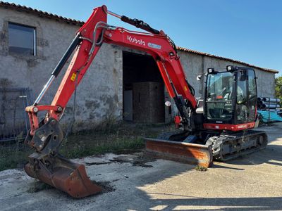 a red excavator that is parked in front of a building