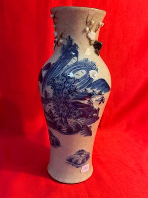 un vase bleu et blanc posé sur un tissu rouge