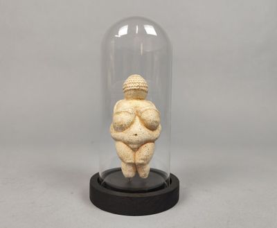 une photo représentant une figurine de femme assise sous un dôme en verre