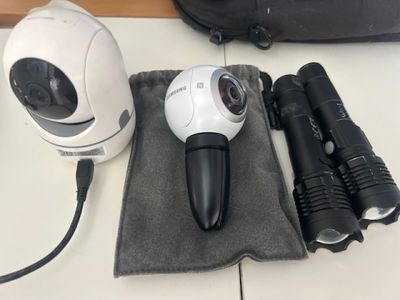 a camera, flashlight, and other items on a table