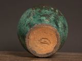 a green vase sitting on top of a wooden table
