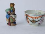 une petite tasse et une petite figurine posées l'une à côté de l'autre