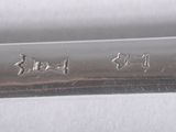a close up of a silver spoon with writing on it
