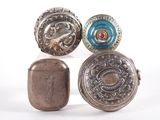 four antique silver and enamel buttons on display on a white surface