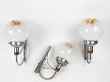 three wall lights with glass globes on each of them on a white surface