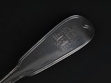 a silver spoon with a metal handle on a black surface