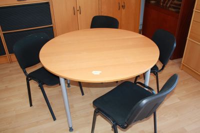 a round table with four chairs around it in a room