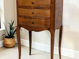 une petite commode dans une pièce où se trouve une plante en pot dans un coin