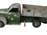 un petit camion jouet vert posé sur une surface blanche