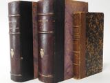 several old books are lined up in a row on a white surface