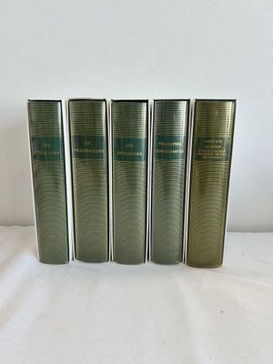 quatre livres sont alignés sur une surface blanche