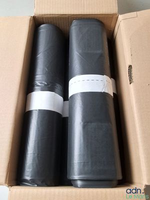 deux rouleaux de plastique noir posés dans une boîte en carton sur une table