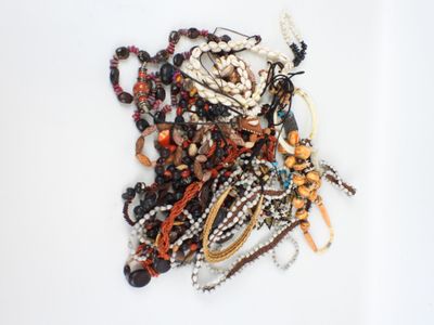 un tas de perles et de bracelets de toutes sortes posés sur une surface blanche