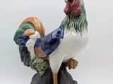 une figurine représentant un coq debout sur un rocher