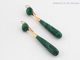 a pair of green and gold earrings on a white surface