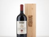 the bottle of red wine is next to a wooden box