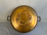 a large metal bowl with handles on a white surface