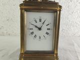 a small gold clock with roman numerals on the face