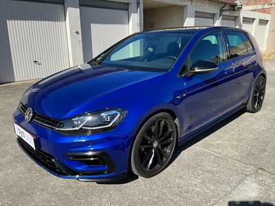 a blue volkswagen golf r line parked in front of a garage