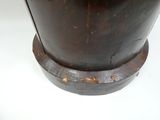 un vase marron posé sur un socle en bois, sur une surface blanche