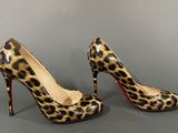 leopard print high heels with red soles on a grey background