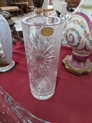 un vase en verre posé sur une table, à côté d'un autre vase posé sur une table