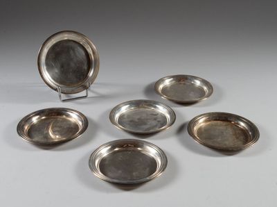 six assiettes en métal argenté et un plat en argent sur un support