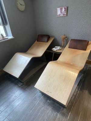two lounge chairs in a room with a clock on the wall