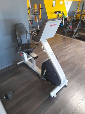 une photo d'une salle de sport avec un vélo d'appartement