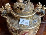 a gold and red vase on a table with a price tag