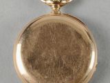 a gold pocket watch with a chain on a gray surface
