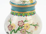 une image représentant un vase blanc orné d'un couvercle bleu et de fleurs