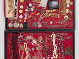 a red box filled with lots of jewelry on a white surface
