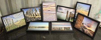 six photos encadrées représentant une scène de plage, posées sur une table
