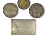three coins and a plaque with a picture of a man and a woman
