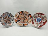 three plates with different designs on them sitting on a white surface