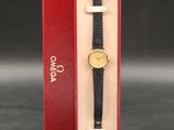 une photo d'une montre noire et dorée dans un coffret rouge