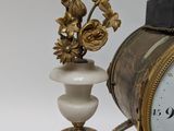 a clock that is sitting next to a vase with flowers in it