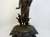 statue en bronze représentant une femme tenant un oiseau, posée sur un socle