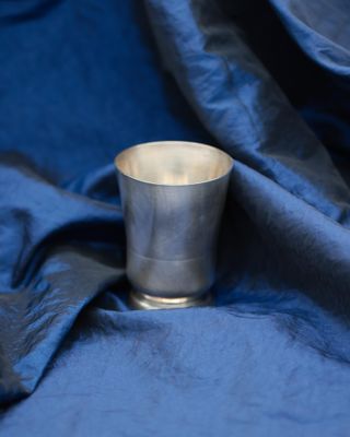 a silver cup that is sitting on a blue cloth