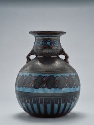 un vase bleu et noir posé sur une surface blanche