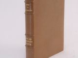 an old book sitting on top of a white surface with a brown cover