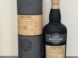 La bouteille se trouve à côté de la boîte en carton sur la table.