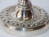a silver plate with a silver candle holder on top of it