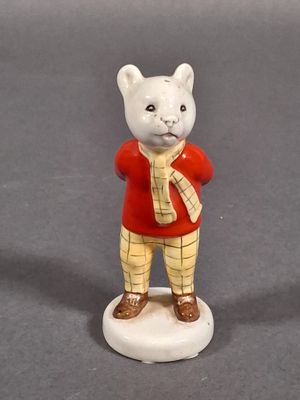 une figurine représentant un chat vêtu d'un t-shirt rouge et d'un pantalon jaune