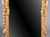 On voit un miroir richement sculpté sur fond gris.